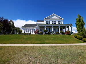 Two-story white residence featuring a columned front porch and dark green shutters