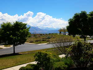 Mountain range backdrop with a clear blue sky, featuring paved streets, mature trees, and natural landscaping