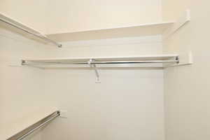 Corner closet system featuring multiple white shelves and chrome hanging rods