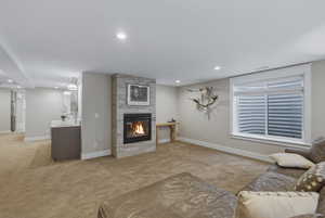 Living area featuring a floor-to-ceiling stone-faced fireplace, recessed lighting, and a neutral carpet