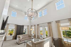 Living room featuring a double-height ceiling, an oversized chandelier, recessed lighting, and multiple large windows