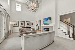 Vaulted living area featuring a contemporary chandelier, electric fireplace with a tiled surround, and a white mantel