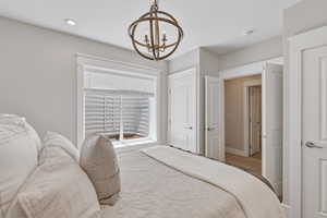 Room featuring a window with blinds, a bronze-finish spherical chandelier, recessed ceiling lighting, and multiple interior doors with white trim