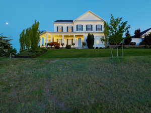 Two-story colonial residence featuring a prominent gabled roofline, white siding, and dark green louvered shutters