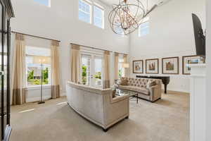 Vaulted ceiling with high transom windows, a multi-tiered chandelier, and a ceiling fan