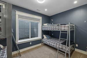 Recessed lighting illuminates this room featuring plush carpet flooring and a basement window with white trim