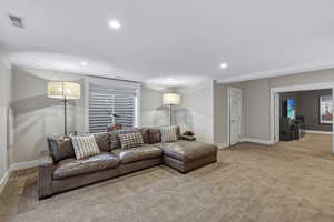 Spacious living area featuring neutral wall tones, recessed lighting, and soft carpet flooring
