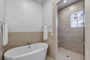 Contemporary bathroom featuring a freestanding soaking tub with polished chrome fixtures, and a spacious walk-in shower with a rain showerhead, built-in shelving, and light-toned tilework