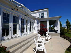 Expansive patio with multiple French doors, gooseneck wall sconces, and a multi-level concrete surface