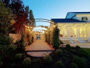 Outdoor recreational path featuring an arched pergola with string lighting, bordered by manicured greenery