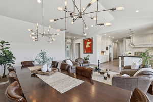Spacious open-concept living area featuring a vaulted ceiling and two contemporary sputnik chandeliers