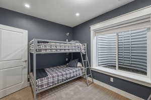 Bedroom featuring dark gray wall paint, white trim, recessed lighting, and a window with a window well