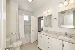 Bathroom featuring a double vanity with stone countertops, undermount sinks, and white cabinetry