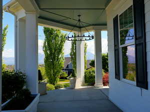 Covered front porch featuring a decorative chandelier, white siding, and black window shutters