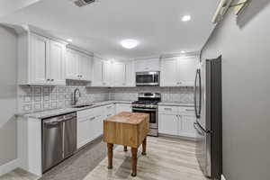 Kitchen featuring white shaker cabinetry, stainless steel appliances, granite countertops, and a patterned tile backsplash