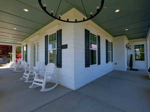 Expansive covered porch featuring a plank ceiling with recessed lighting and a decorative chandelier