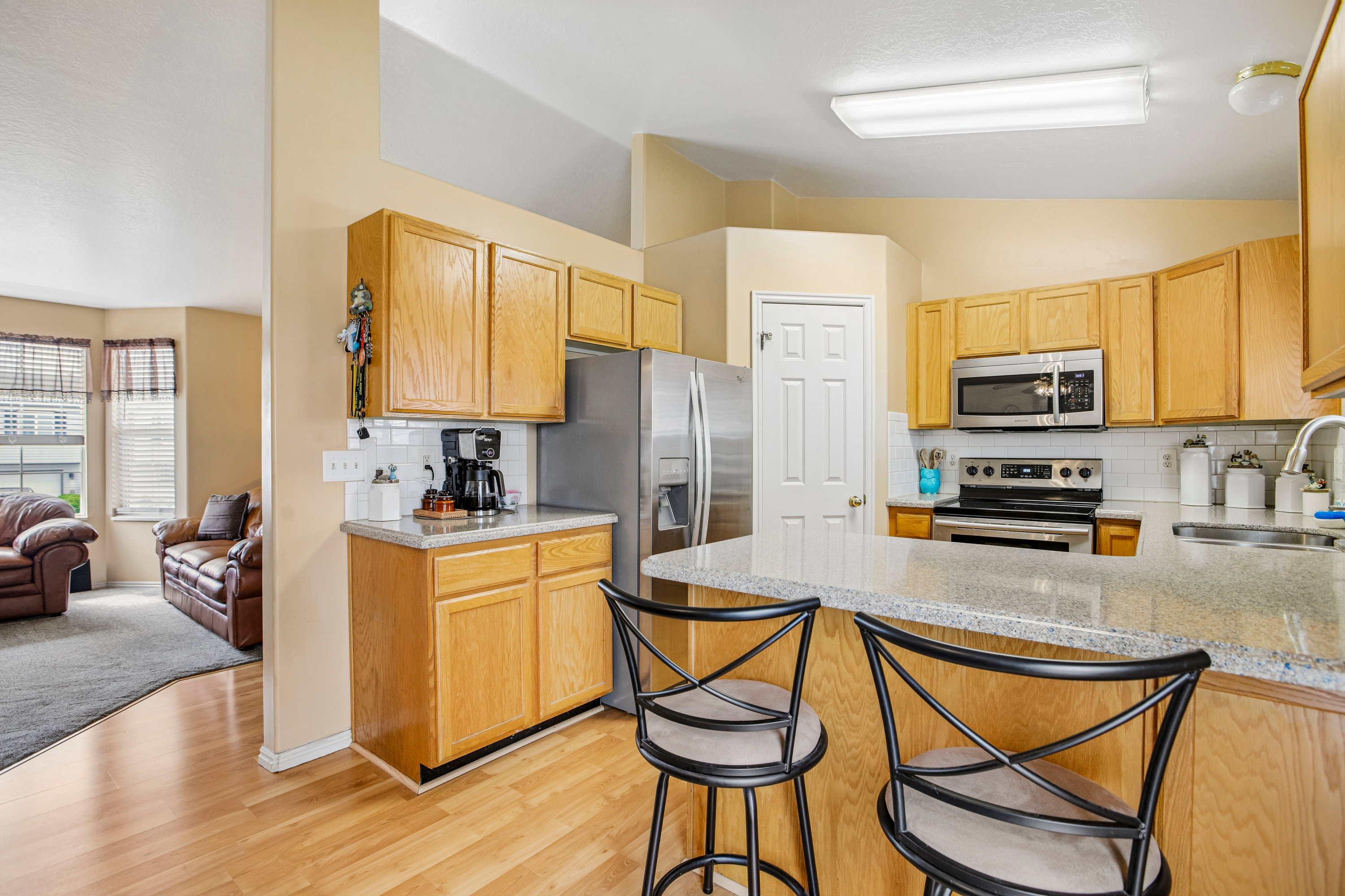 Kitchen featuring light wood cabinetry, light-colored countertops, stainless steel appliances, and a white subway tile backsplash