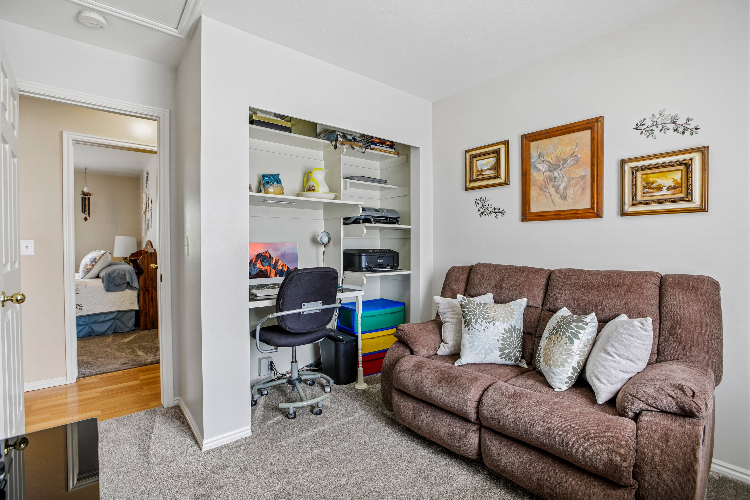 Dedicated office nook with built-in shelving, soft gray carpeting, and light wall paint