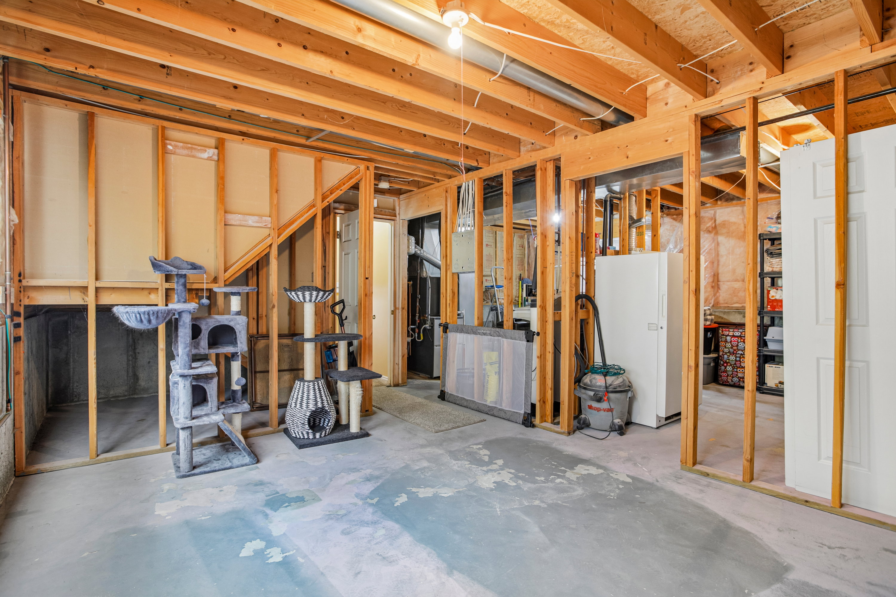 Unfinished basement featuring exposed wood framing, concrete flooring, and an open ceiling