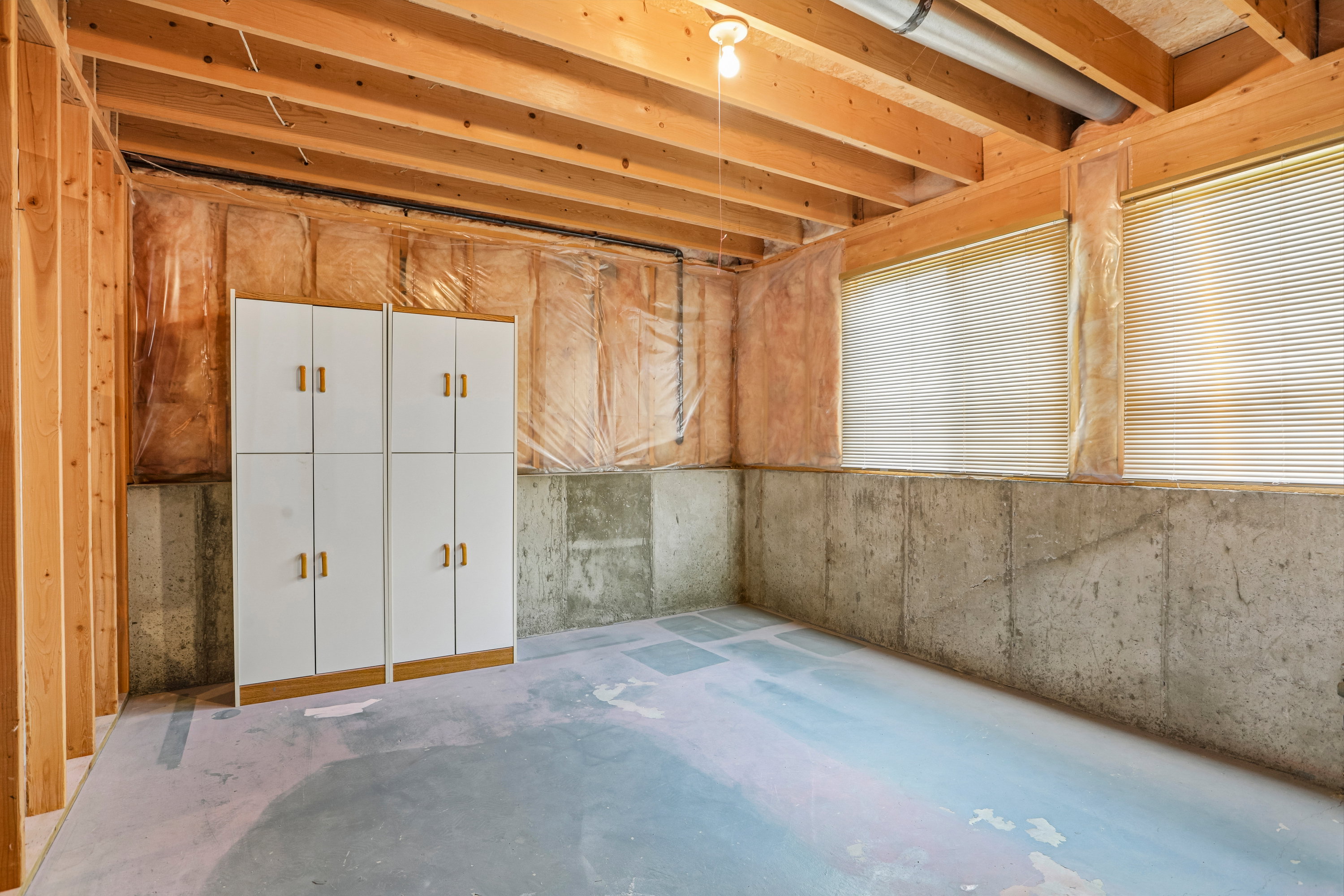 Unfinished basement with exposed wood joists and concrete walls