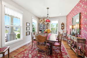Dining room featuring wood-finish flooring, white trim, and a patterned accent wall
