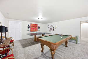 Spacious recreation room featuring light gray carpeting, white painted walls, and an overhead flush-mount light fixture