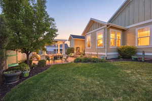 Expansive rear yard featuring a manicured lawn, established landscaping, and a paver patio with a white pergola