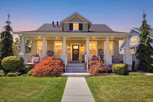 Exterior featuring a covered porch with white columns, light green siding, and dark shutters