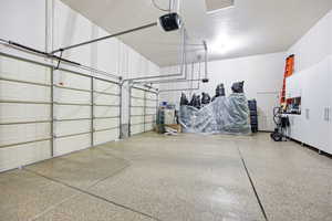 Spacious garage featuring two overhead doors, a finished floor, and built-in white cabinetry