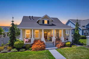 Craftsman-style home featuring a covered front porch with white columns, a dark wood entry door, and dormer window