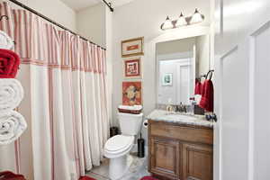 Bathroom featuring a wood-finish vanity with a speckled countertop, an undermount sink, and a framed mirror