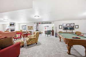 Expansive lower level recreation room featuring a billiard table, a built-in fireplace, and recessed windows