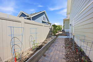 Paved brick walkway bordered by a raised garden bed and a mulch-covered planting area