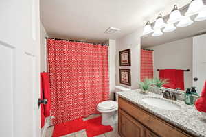 Bathroom featuring a wood-finish vanity with a granite countertop, undermount sink, and bronze-finish faucet
