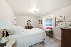 Spacious bedroom featuring light neutral wall tones and textured carpeting