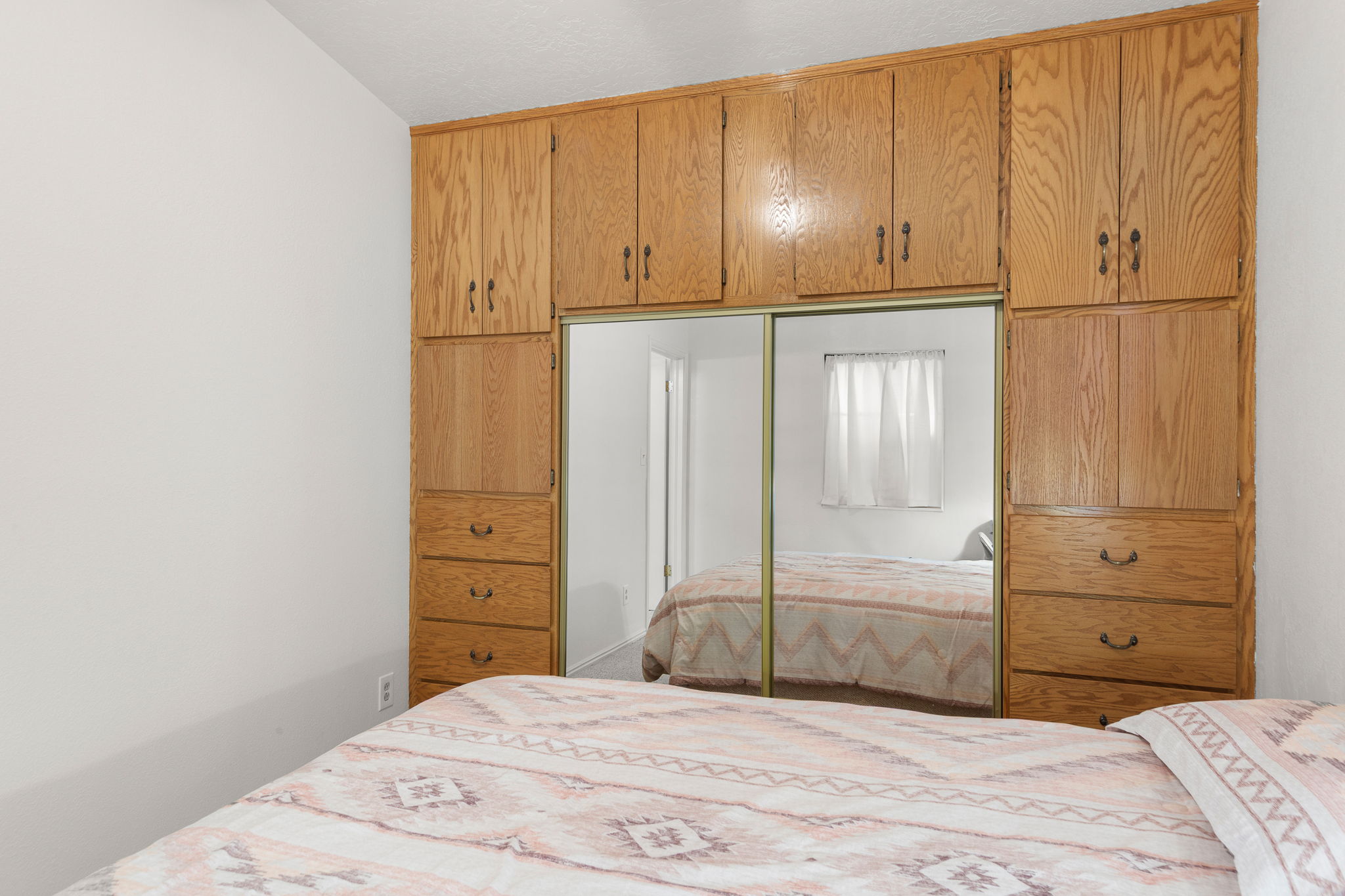 Built-in wood cabinetry with integrated mirrored sliding doors, multiple storage compartments, and wood-finish drawer units