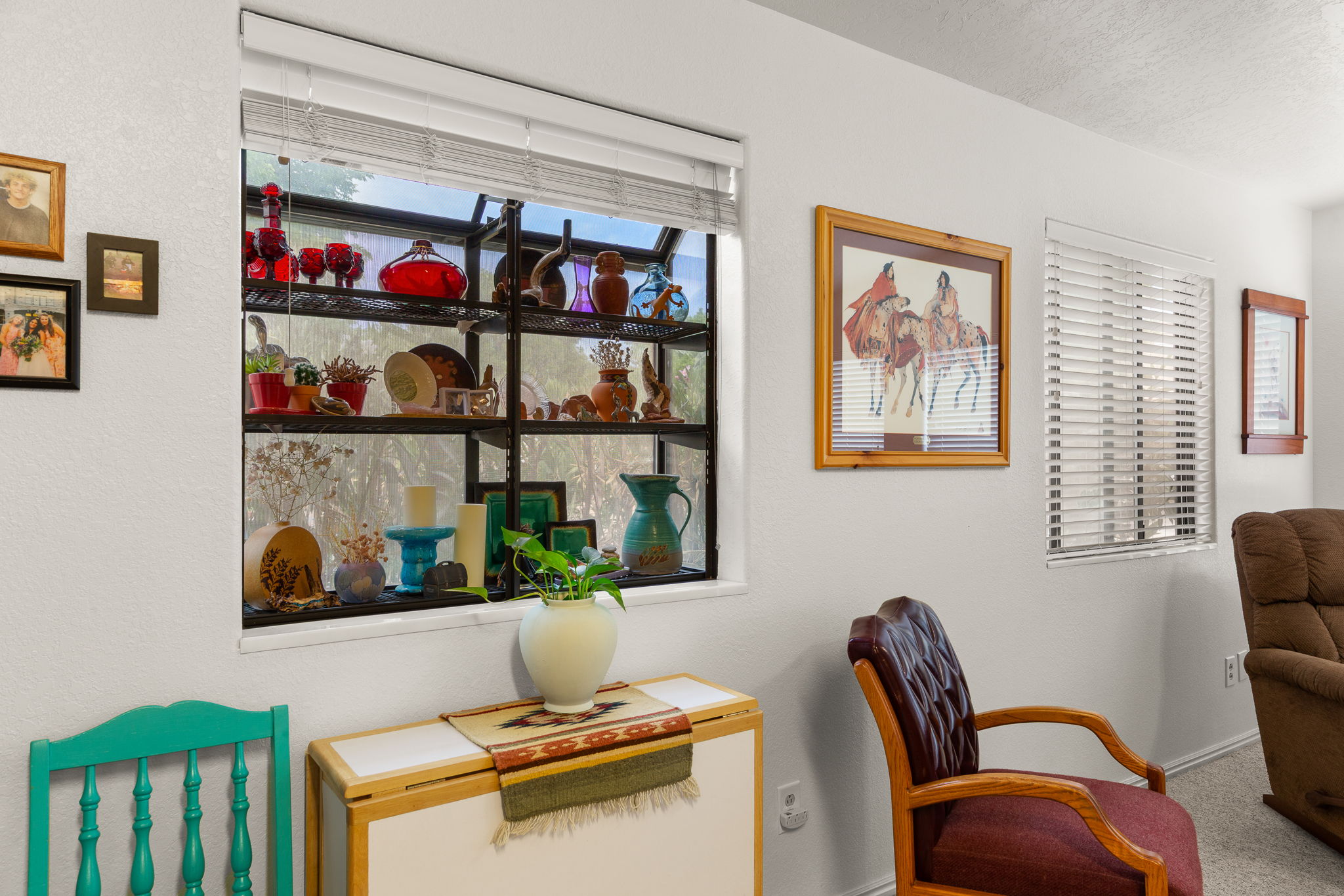 White walls with multiple windows, including a large window with built-in shelving, providing natural light