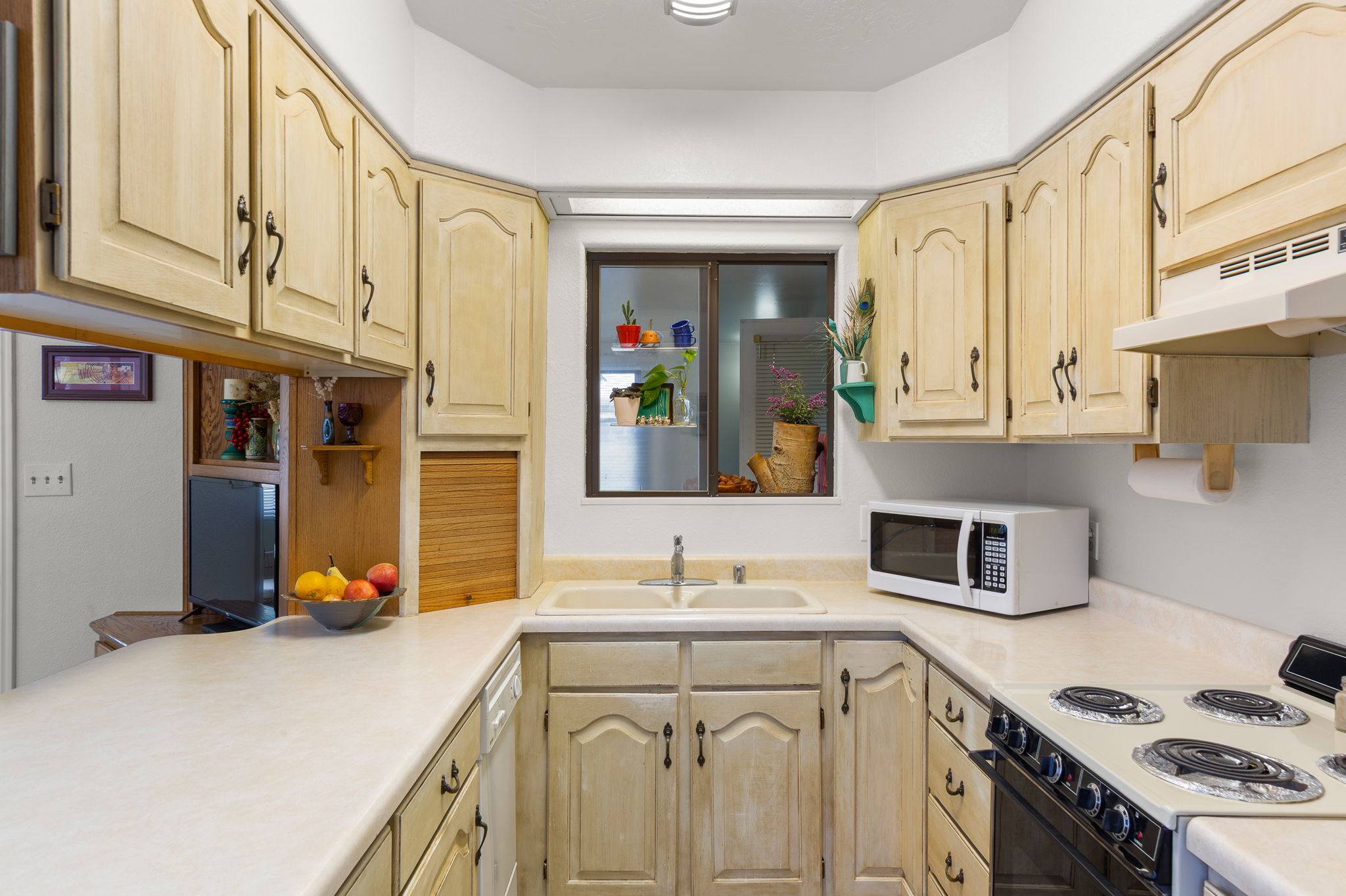 U-shaped kitchen featuring light-finish cabinetry, a double basin sink, and a built-in electric range