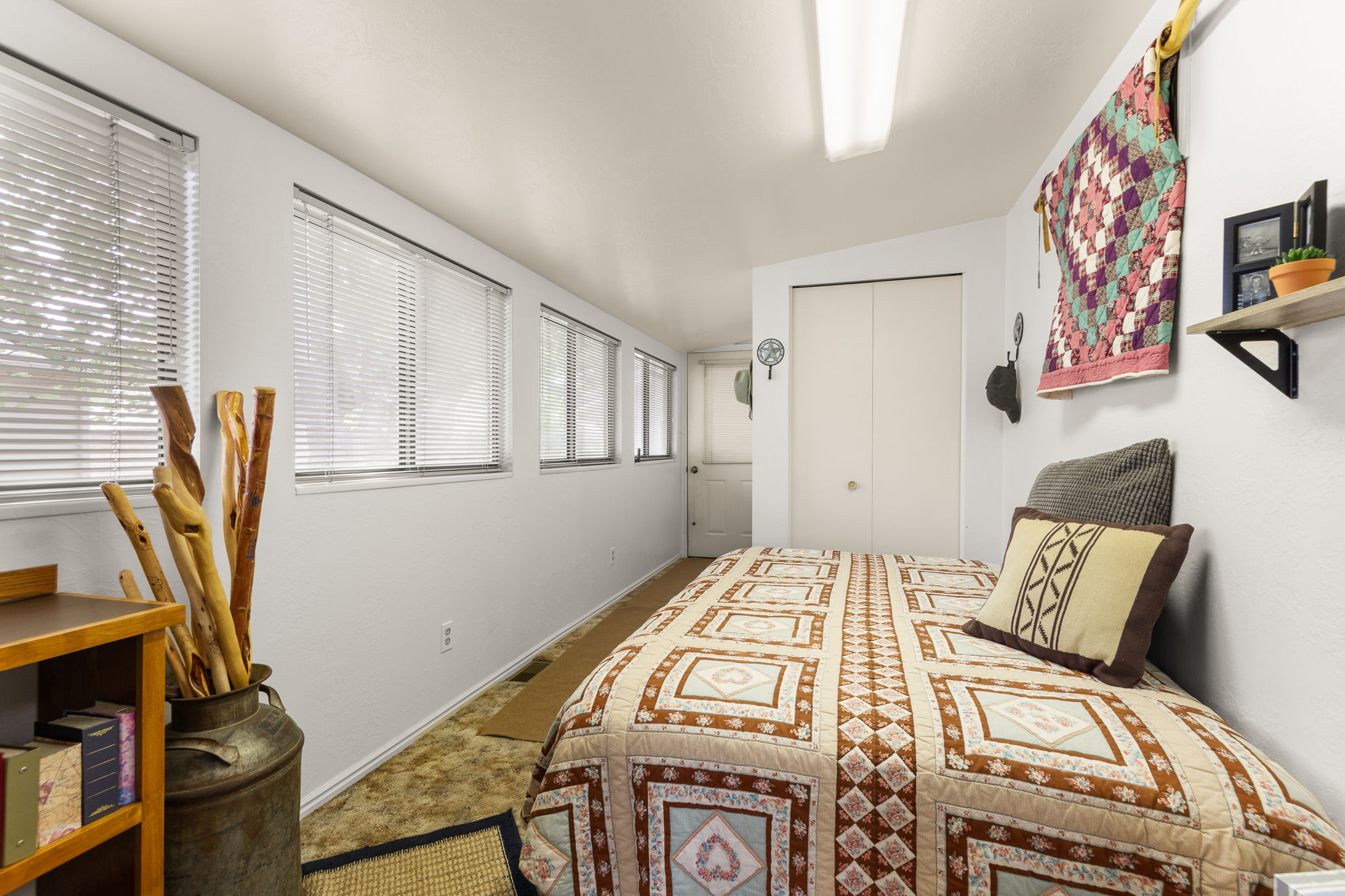 White walls, recessed lighting, and a row of windows with blinds define this space