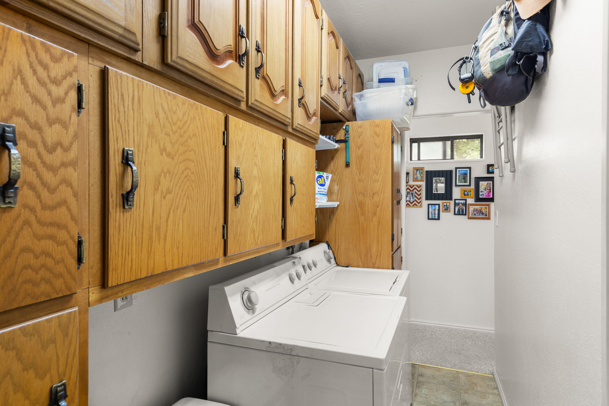 Utility room featuring extensive wood cabinetry, white walls, and a window providing natural light