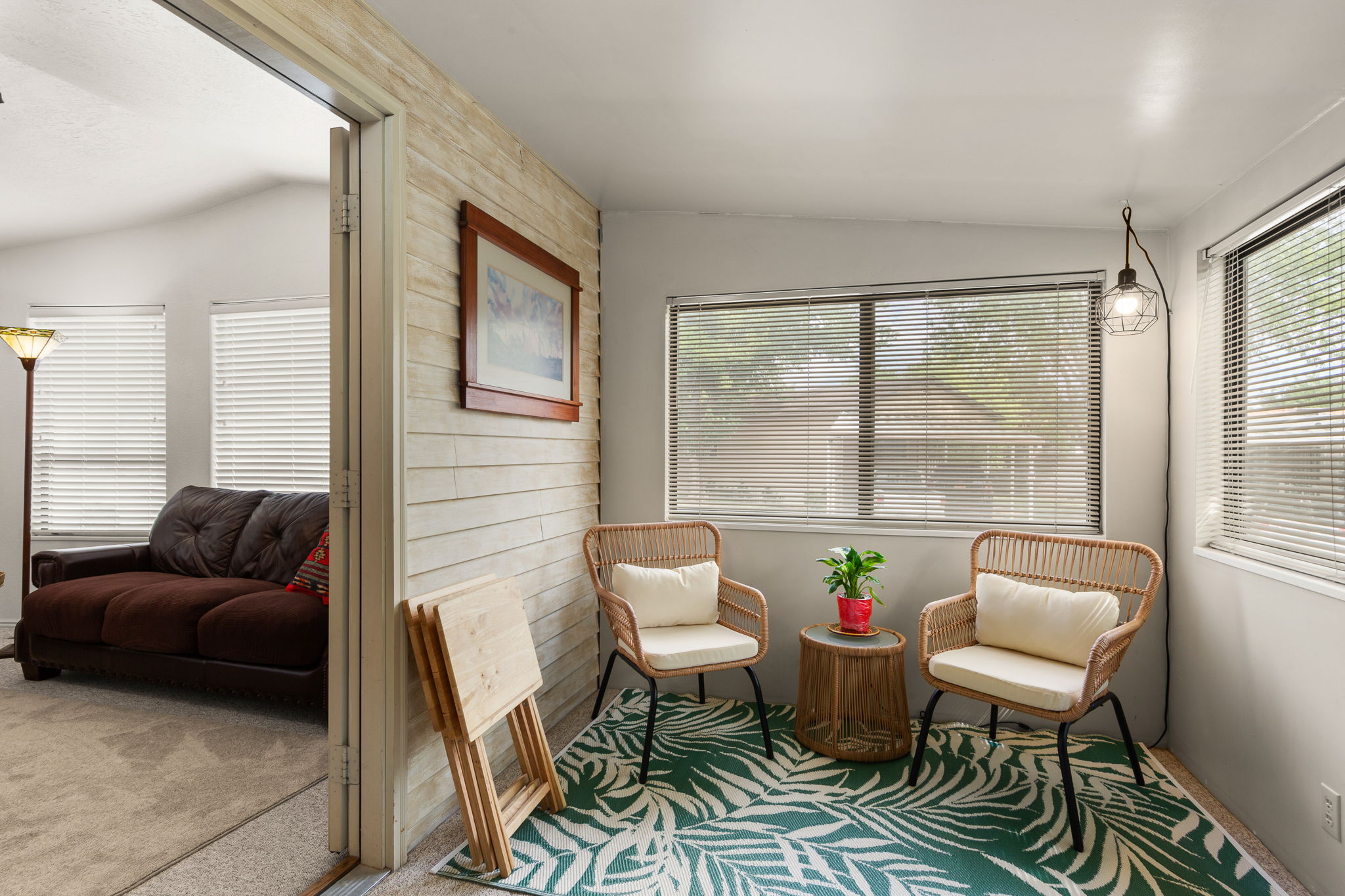 Sunlit sitting area featuring a shiplap accent wall, multiple windows with blinds, and a contemporary wall-mounted light fixture