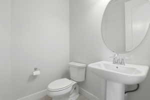 Pedestal sink with chrome faucet, oval mirror, and white toilet