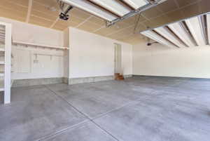 Spacious garage featuring a concrete floor, built-in shelving, overhead lighting, and an automatic garage door opener