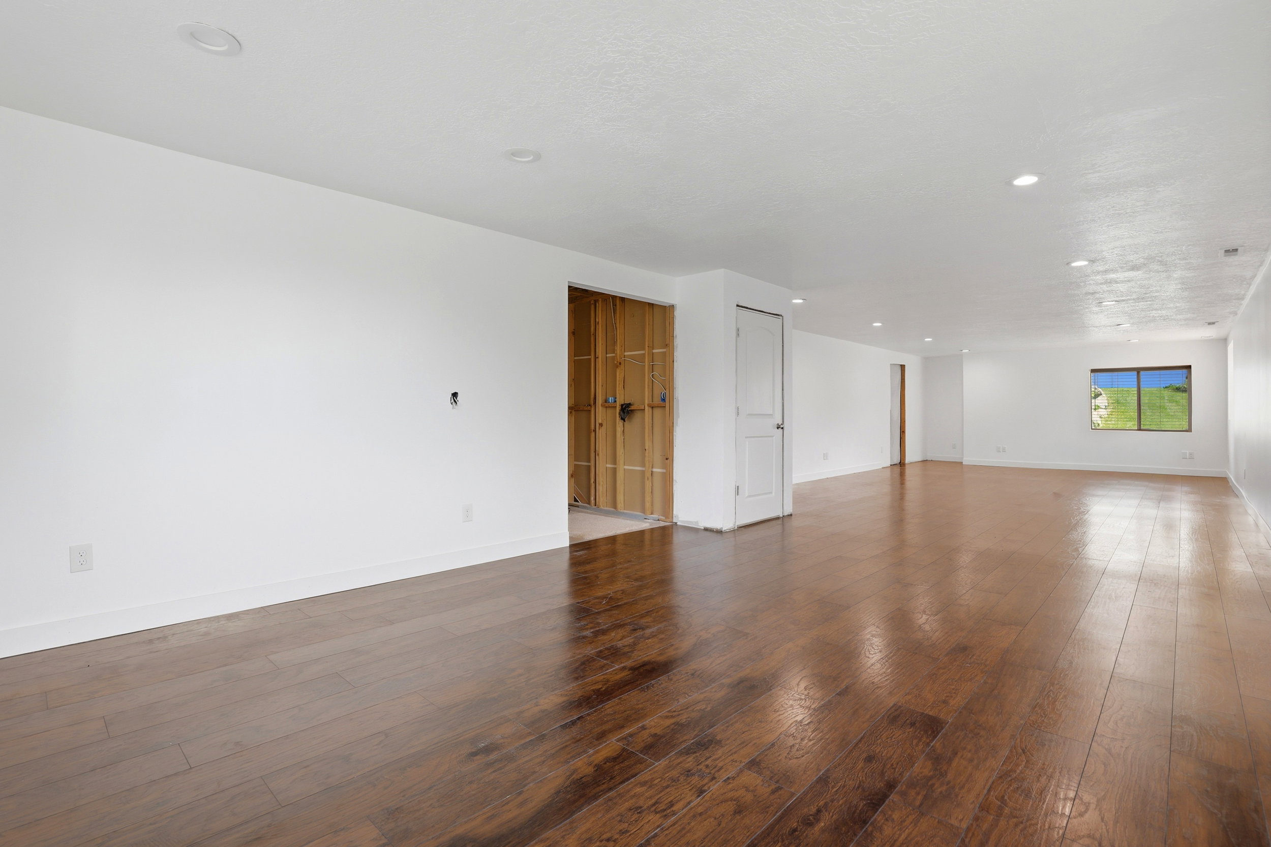 Spacious room featuring wood-finish flooring, recessed lighting, and a neutral color palette