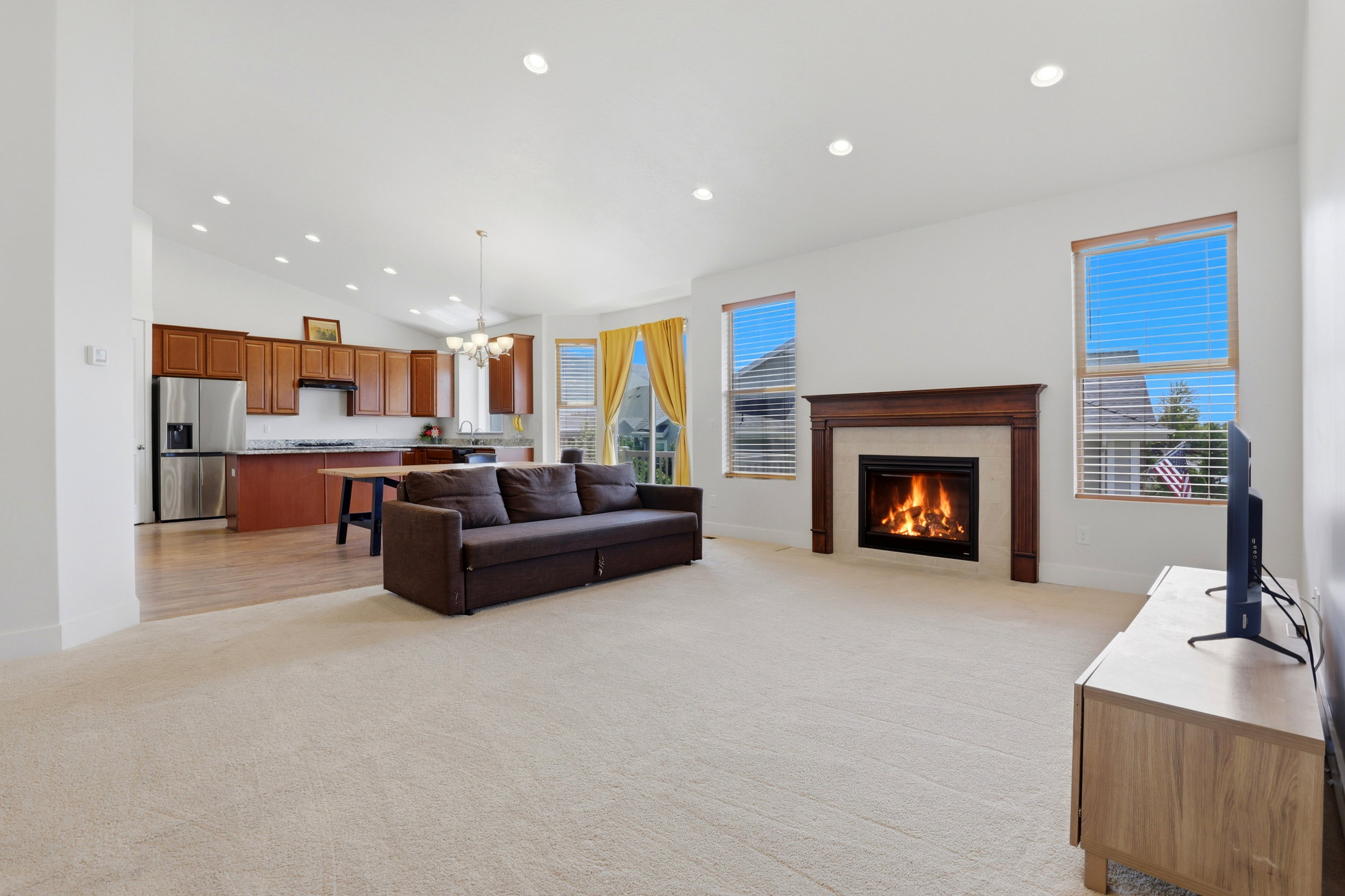 Expansive living area featuring a gas fireplace with wood mantel and tile surround, vaulted ceiling, and recessed lighting