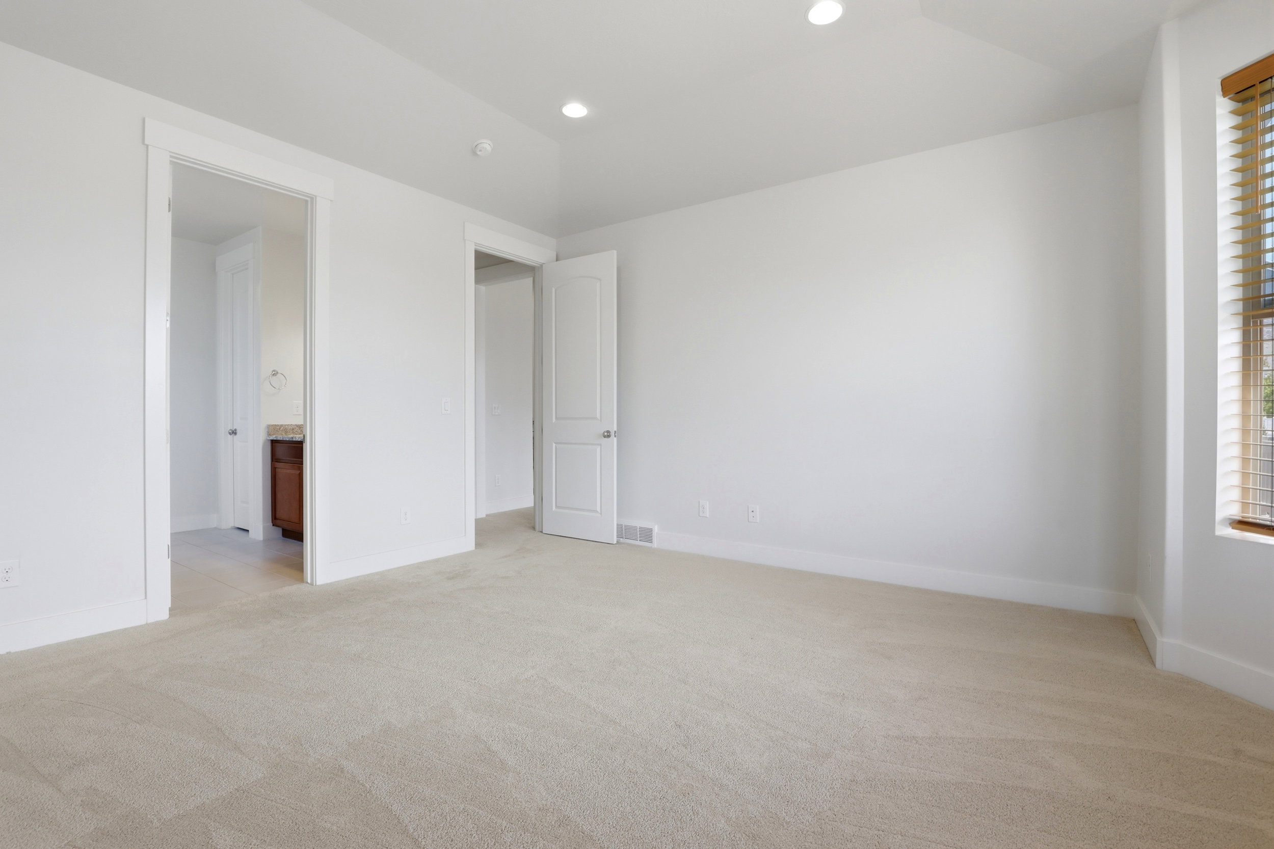 Carpeted room featuring white walls, recessed lighting, and a window with wood-finish blinds