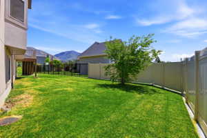 Expansive backyard with a manicured lawn, featuring a partial privacy fence and an open-air deck
