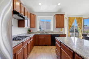 Kitchen featuring wood-finish flooring, ample wood cabinetry, and granite countertops