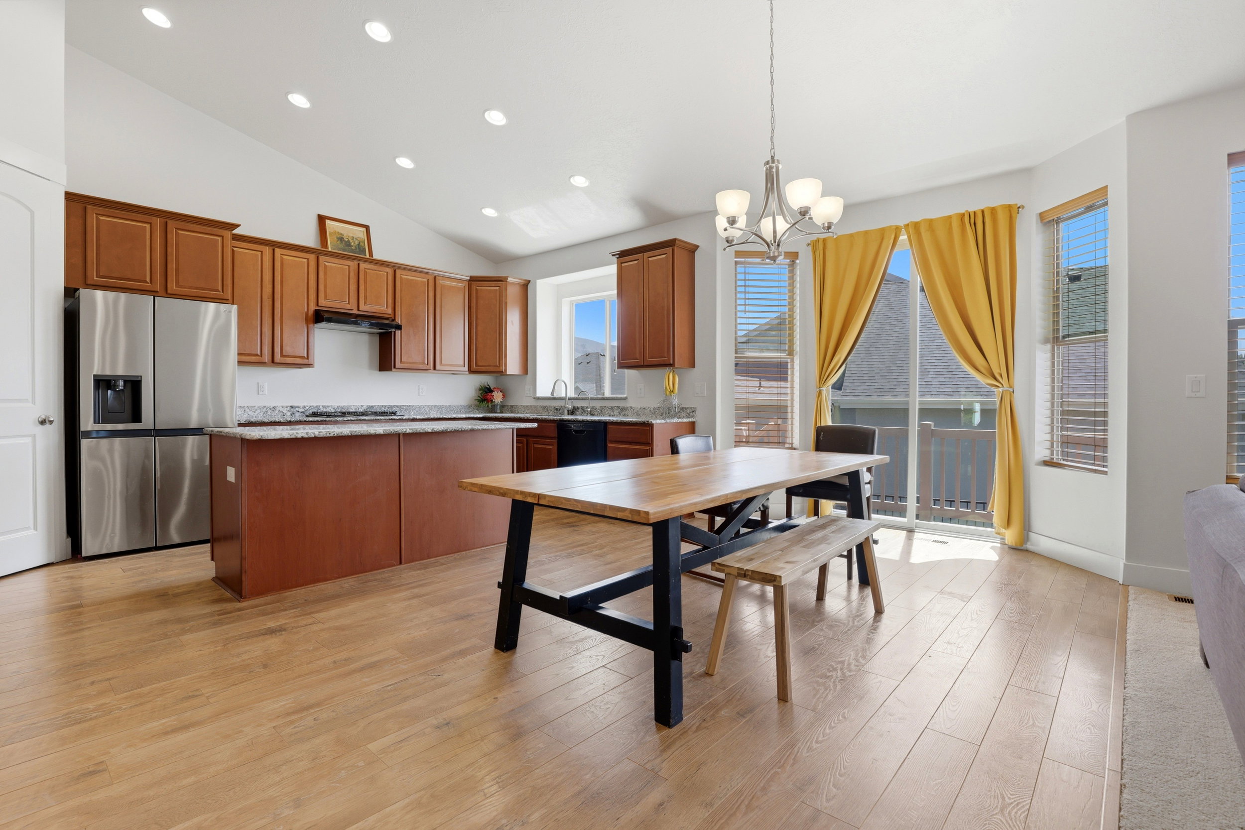 Open-concept kitchen and dining area featuring wood-finish flooring, vaulted ceilings, and recessed lighting