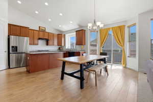 Open-concept kitchen and dining area featuring wood-finish flooring, vaulted ceilings, and recessed lighting